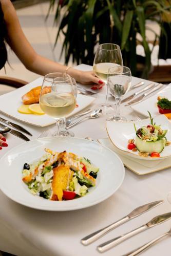 a table with plates of food and glasses of wine at Hotel Afa in Pristina