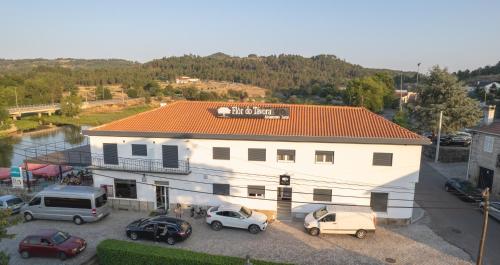 a white building with cars parked in a parking lot at Flôr do Távora in Vila da Ponte