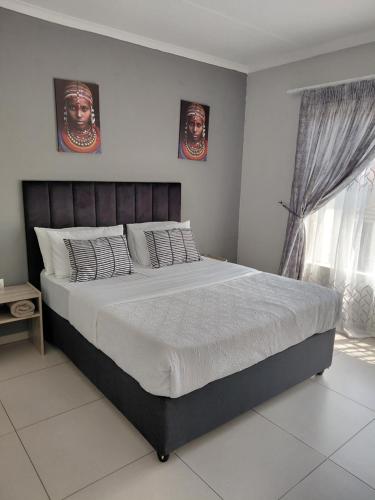 a bedroom with a large bed with two portraits on the wall at Mama R's unit 39 in Newcastle