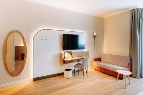 a room with a desk and a couch and a mirror at Mövenpick Hotel Bari in Bari