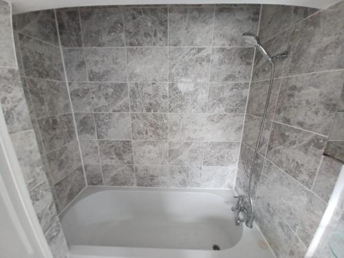 a shower with a white tub in a bathroom at The Maple in Grays Thurrock
