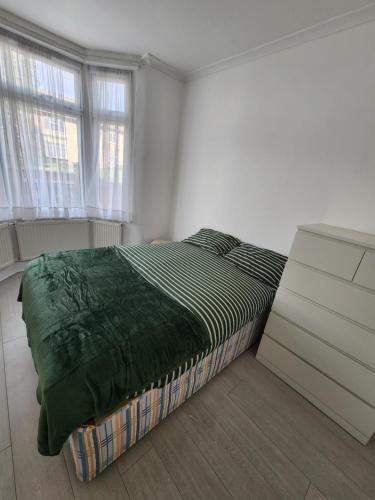 a bedroom with a bed and a dresser and two windows at The Maple in Grays Thurrock