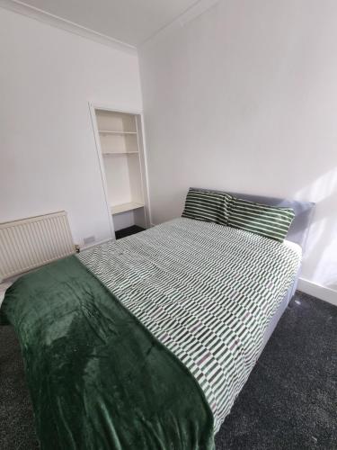 a bedroom with a large bed with a green blanket at The Maple in Grays Thurrock