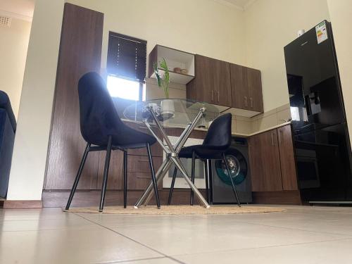 a kitchen with two chairs and a glass table at Wentworth star in Roodepoort