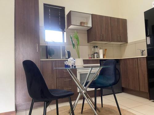 a kitchen with two chairs and a glass table at Wentworth star in Roodepoort