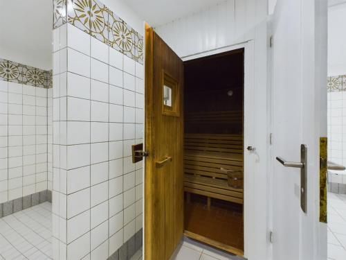 a wooden door in a bathroom with white tiles at Wellenkieker in Wyk auf Föhr