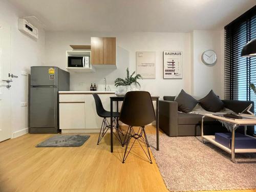 a kitchen and living room with a couch and a table at Bedsment กัลปพฤกษ์ แกรนด์ พาร์ค เชียงราย in Ban Nong Chaeng