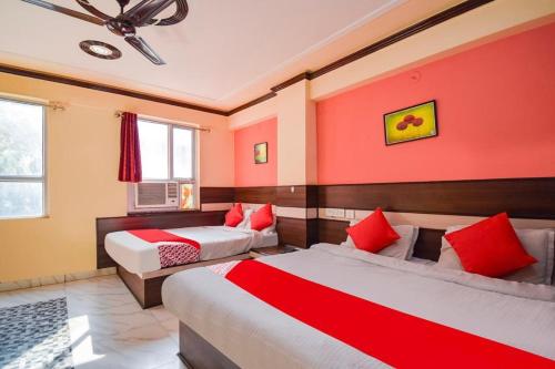 a bedroom with two beds and red walls at Hotel Churu Palace in Jaipur