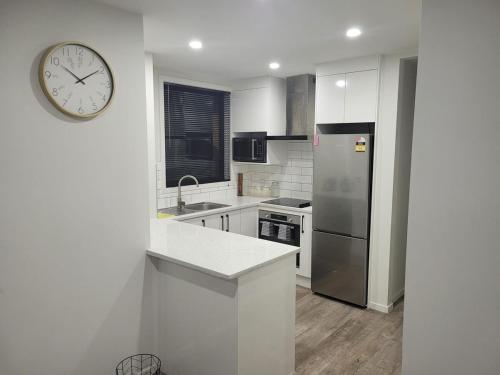 a white kitchen with a clock on the wall at Welcome to your cozy retreat! two-bedroom home in Flagstaff in Hamilton