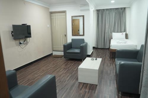 a hotel room with a bed and a couch and a tv at Kanishka Grand in Bengaluru