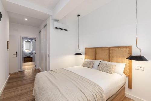 a white bedroom with a large bed and a bathroom at Queens Bernabéu in Madrid