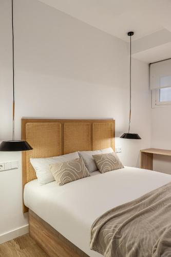 a bedroom with a large white bed with two pendant lights at Queens Bernabéu in Madrid