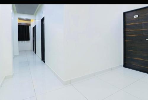 a corridor of a building with black doors and white floors at Hotel Season in Ahmedabad