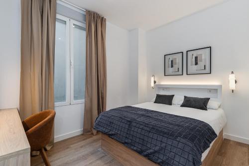 a bedroom with a bed and a chair and a window at Queens Bernabéu in Madrid
