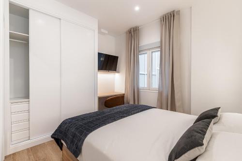 a bedroom with a white bed and a window at Queens Bernabéu in Madrid
