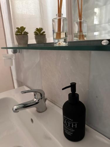 a black bottle of soap sitting on a bathroom sink at Eagles Nest Villa Athenian Riviera in Aghia Marina near Lagonisi, next to the beach close to Athens Airport in Aghia Marina