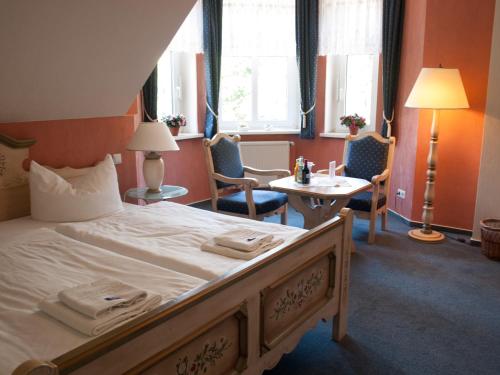 a hotel room with a bed and a table and chairs at Hotel & Restaurant Waldschlösschen in Kyritz