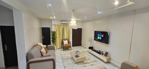 a living room with a couch and a tv on a wall at Winters Apartments in Abuja