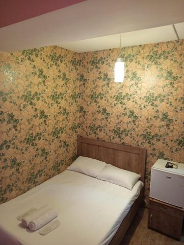 a small bed in a bedroom with floral wallpaper at Kavela555 in Tbilisi City