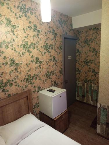 a bedroom with a bed and a wall with floral wallpaper at Kavela555 in Tbilisi City