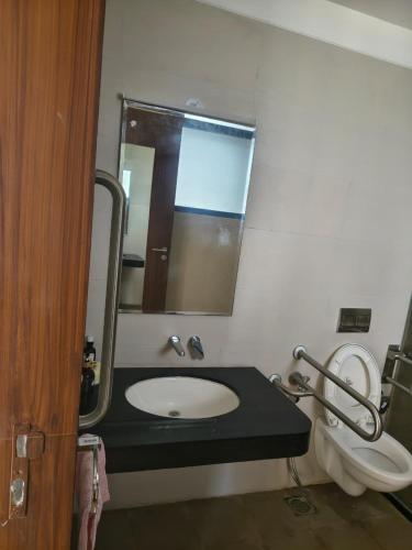a bathroom with a sink and a mirror and a toilet at Abhushan Mahal in Nīmri