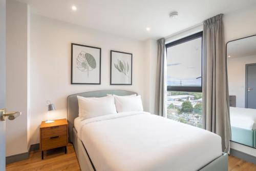 a white bedroom with a bed and a window at Luxury Apartments in a vibrant part of North London in London