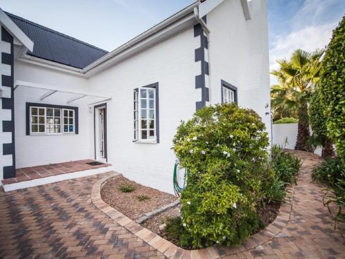 a white house with a brick driveway at Cosimi Guest House in Durbanville