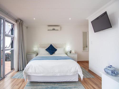 a white bedroom with a bed and a tv at Cosimi Guest House in Durbanville