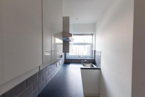 a white kitchen with a sink and a window at Radstock Road - Room 3a in Southampton