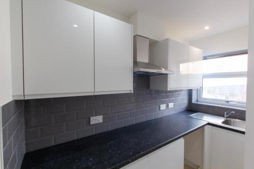 a kitchen with white cabinets and a black counter top at Radstock Road - Room 3a in Southampton