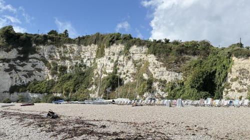 a sandy beach with a mountain in the background at Sea Holly House - Where Architecture Meets the Ocean in Beer