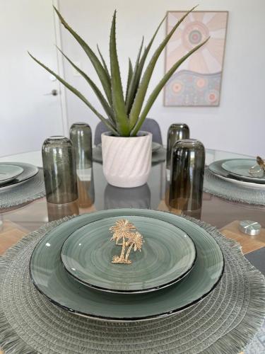 a green plate sitting on a table with a plant at Baldivis Home Close to IGA, CAFE, Restaurants, 15 mins to beach in Baldivis