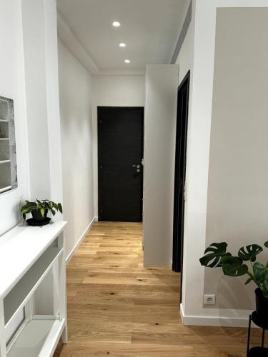 a hallway with a black door and a wooden floor at Carré d'Or - 2P Cosy avec Terrasse et véranda in Nice