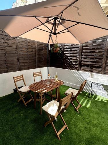 a table and chairs with an umbrella on the grass at Carré d'Or - 2P Cosy avec Terrasse et véranda in Nice