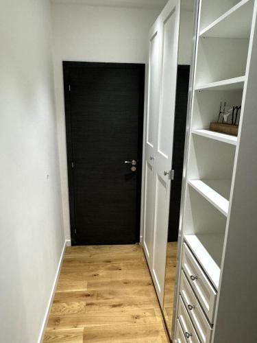 a hallway with a black door and white shelves at Carré d'Or - 2P Cosy avec Terrasse et véranda in Nice