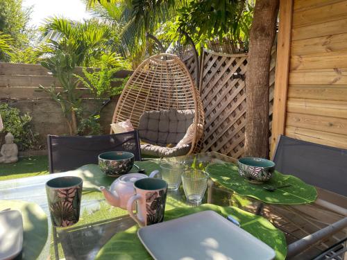 a table with a laptop and cups and a swing at Maisons Familiales 101 m2 et 51 m2 Lagon, Plage & Détente, La Saline-les-Bains in La Saline les Bains