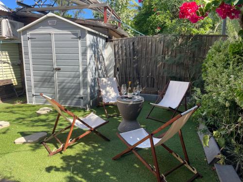 a backyard with chairs and a table and a grill at Maisons Familiales 101 m2 et 51 m2 Lagon, Plage & Détente, La Saline-les-Bains in La Saline les Bains