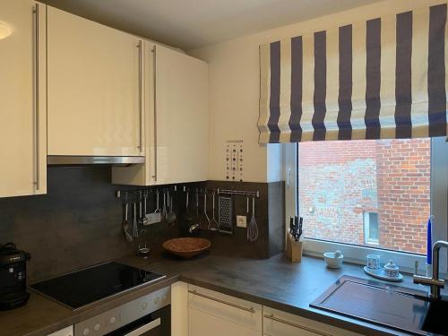 a kitchen with white cabinets and a sink and a window at Exklusive Ferienwohnung im schönen Husum in Husum