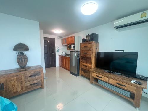 a living room with a large television and a kitchen at Bangsaray Beach Condo B220 บางเสร่ บีช in Bang Sare