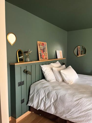 a bedroom with green walls and a bed with white pillows at Les Chambres du parc in Monnières