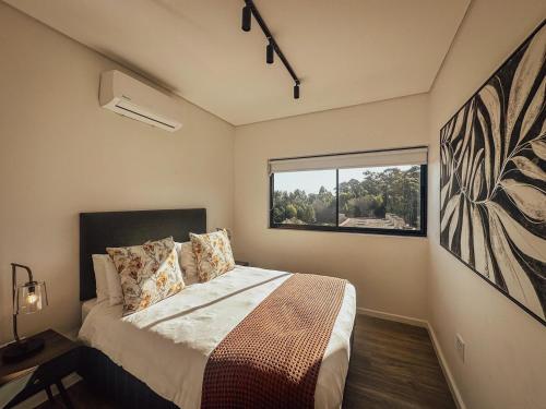 a bedroom with a large bed and a window at Outeniqua View Escape - Le Jardin 304 in George