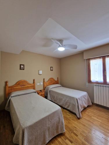 a bedroom with two beds and a ceiling fan at Hostal Valle De Tena in Sabiñánigo