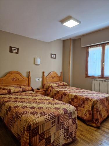 a hotel room with two beds and a window at Hostal Valle De Tena in Sabiñánigo