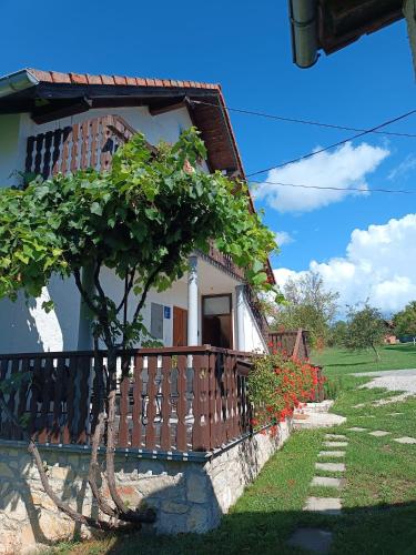 a house with a fence and a tree next to it at Apartman PLUM PLITVICE in Drežnik Grad