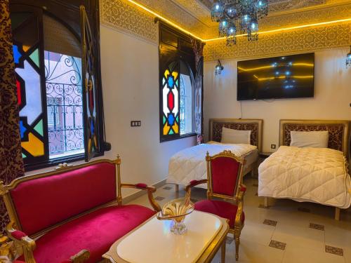 a room with two beds and a table and chairs at Riad Mogador in Meknès