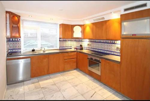 a kitchen with wooden cabinets and a sink and a window at Villa with garden near Amsterdam in Almere