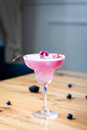a pink drink in a martini glass on a wooden table at Hotel Ilan in Lublin