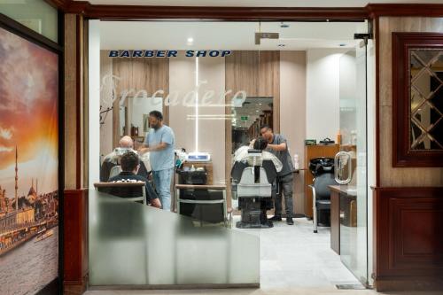 a barber shop with people standing in the window at Al Shohada by Palm Rich Makkah in Makkah