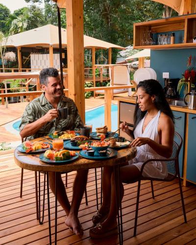 Un uomo e una donna seduti a un tavolo con del cibo di Evia Life Resort a Puerto Viejo