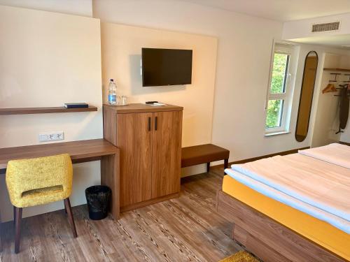 a bedroom with a bed and a desk and a television at Hotel Lamm in Ostfildern